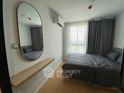 Modern bedroom with large mirror and cozy bedding in a stylish apartment.