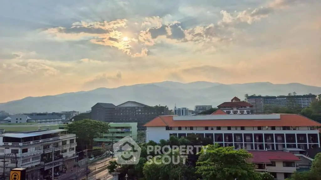 Stunning mountain view from a city rooftop at sunset, showcasing urban and natural beauty.