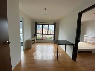 Spacious unfurnished living room with large window and wooden flooring in modern apartment.