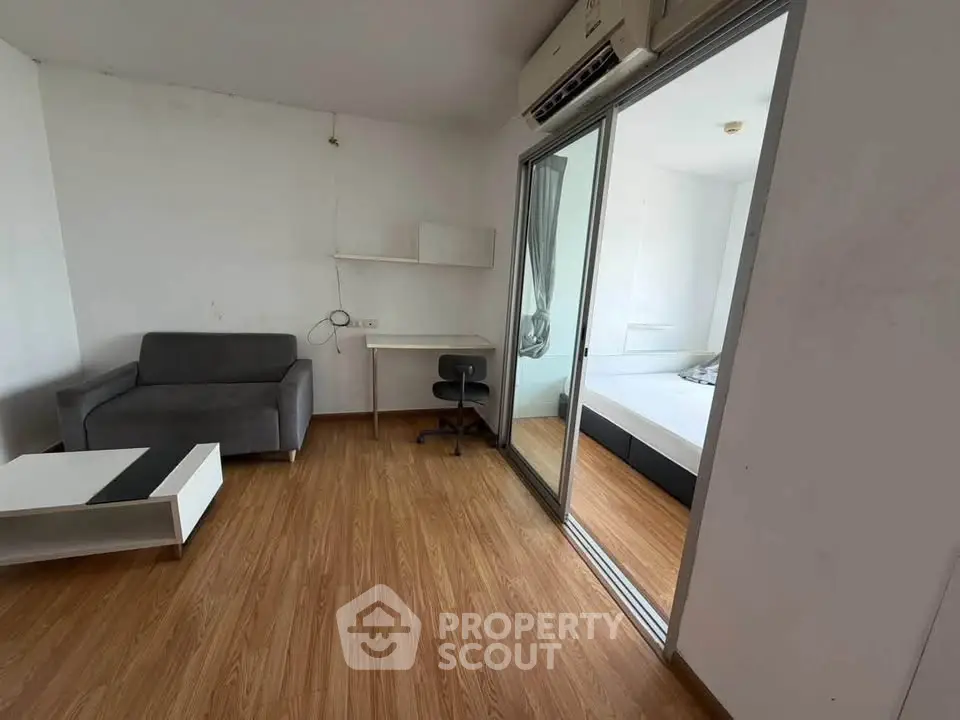 Modern apartment with wooden flooring, sliding glass doors, and minimalist furniture.