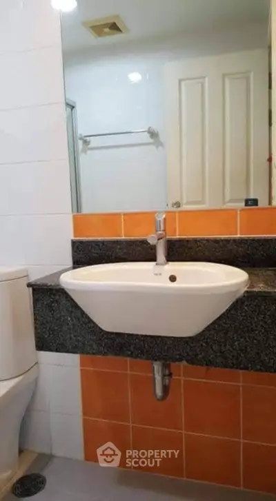 Modern bathroom with sleek sink and vibrant orange tiles