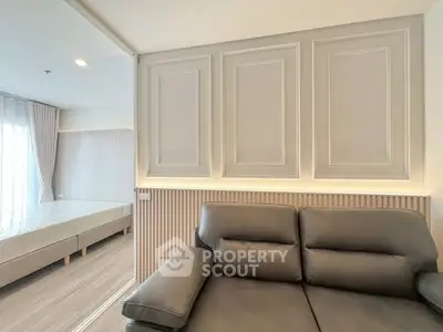 Modern living room with elegant paneling and cozy sofa, adjacent to a bright bedroom.