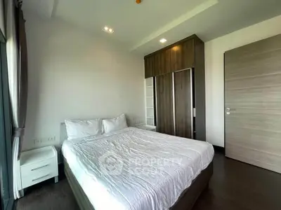 Spacious bedroom with modern wardrobe and large window for natural light.