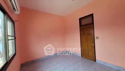 Spacious empty room with peach walls and large window, perfect for customization.