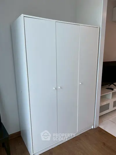 Modern white wardrobe in a stylish living room with wooden flooring and TV unit.