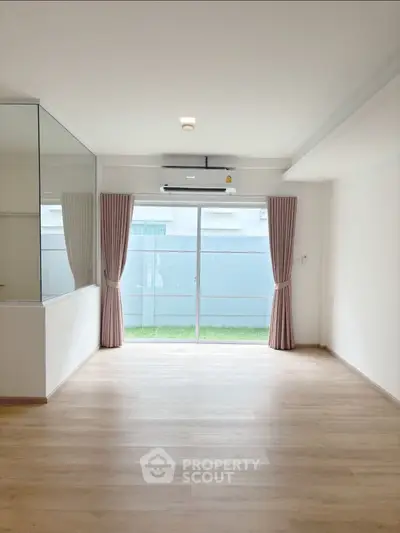 Spacious empty room with large window and garden view, perfect for customization.