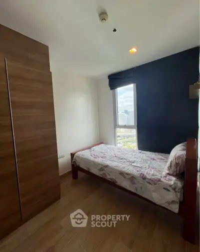 Cozy bedroom with city view and wooden wardrobe, perfect for urban living.