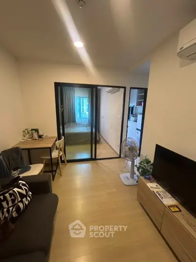 Cozy modern apartment with open living room and bedroom, featuring sleek glass partition and stylish decor.