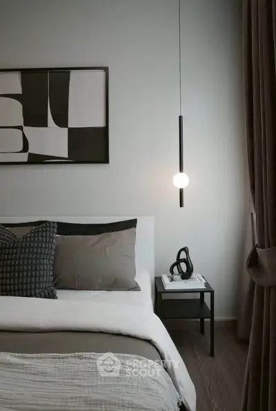 Modern bedroom with stylish decor and cozy ambiance, featuring a sleek pendant light and abstract wall art.