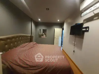 Cozy bedroom with a large bed, elegant headboard, and modern amenities including air conditioning and wall-mounted TV.