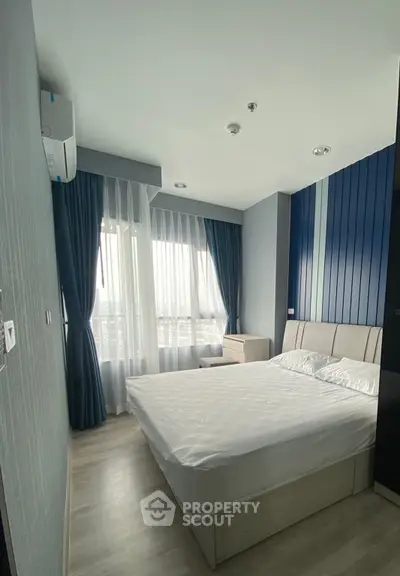 Modern bedroom with large window and stylish blue accents in a contemporary apartment.