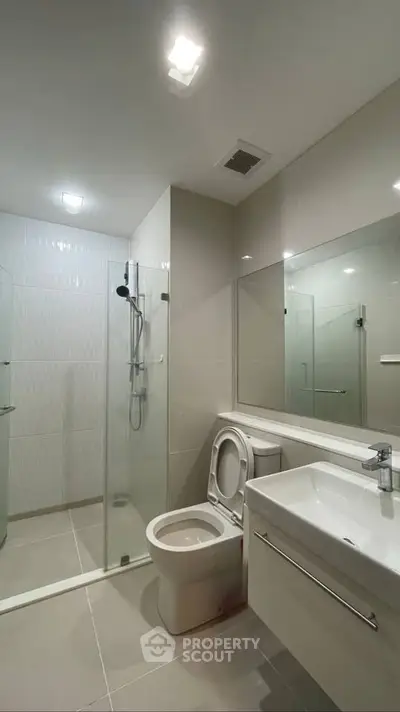Modern bathroom with glass shower and sleek fixtures in contemporary apartment.