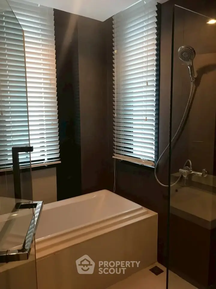 Modern bathroom with sleek design and bathtub, featuring stylish blinds and a glass shower enclosure.