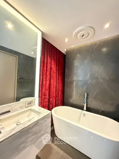 Luxurious bathroom with elegant freestanding bathtub and marble sink, featuring modern design and rich red curtains.