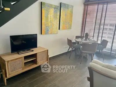 Modern living room with stylish decor and dining area, featuring large windows and contemporary furniture.