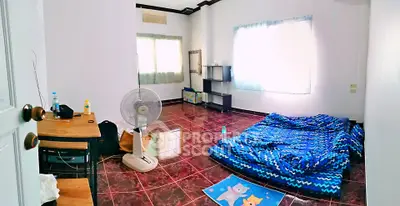 Spacious bedroom with tiled floor, simple furnishings, and natural light.