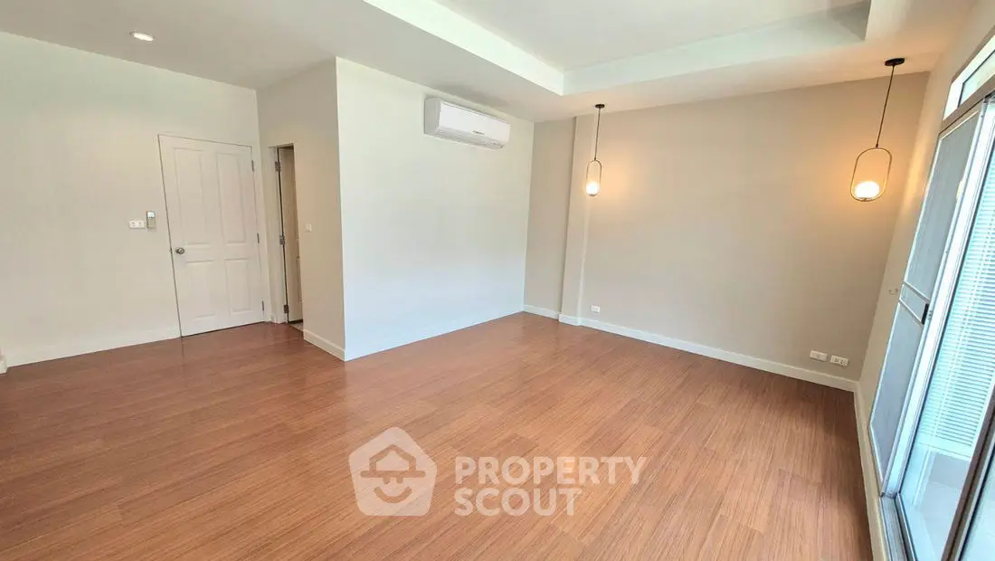 Spacious empty room with wooden flooring and modern lighting, ideal for customization.