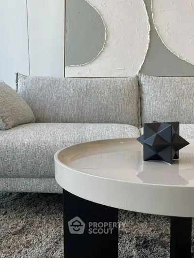 Modern living room with stylish gray sofa and geometric decor on sleek coffee table.
