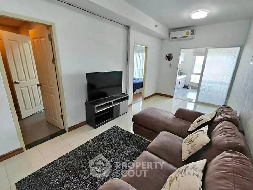 Cozy living room with plush sofa and modern TV setup in a bright apartment.