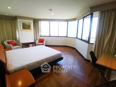 Spacious bedroom with large windows and elegant wood flooring in a modern apartment.