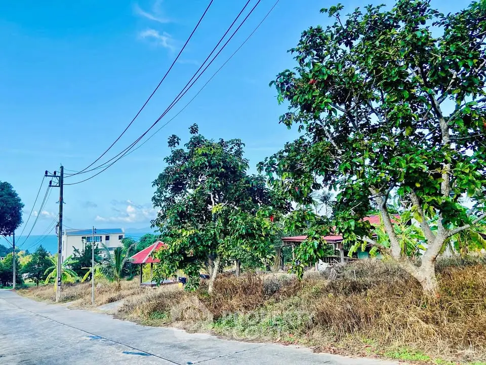 Scenic view of lush greenery and distant building under clear blue sky