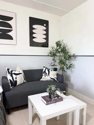 Stylish living room with modern decor, featuring a sleek gray sofa, chic artwork, and a vibrant indoor plant.