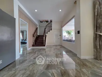 Spacious modern living area with elegant staircase and large windows for natural light.