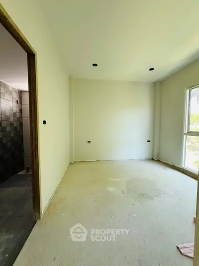 Spacious unfinished room with large window and adjacent tiled bathroom, ideal for customization.