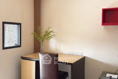 Modern study room with sleek desk and chair, featuring a small window and decorative plant.