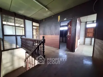 Spacious interior with wooden staircase and vintage charm, ideal for renovation projects.