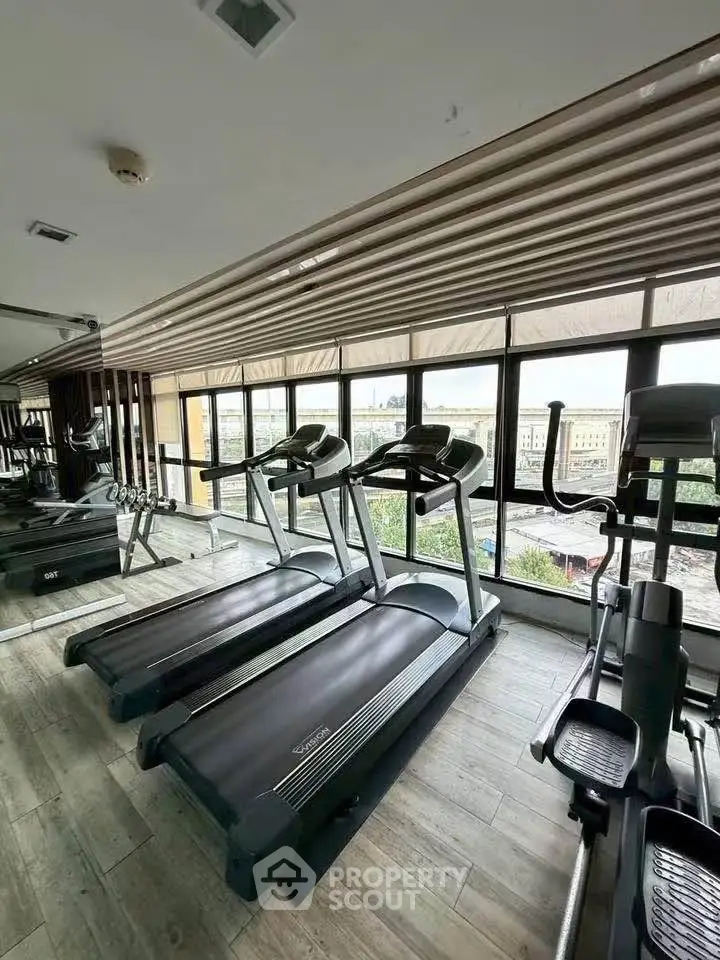 Modern gym with treadmills and large windows offering city views in a luxury residential building.