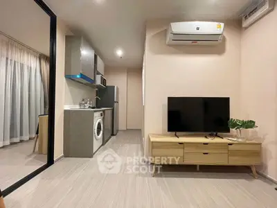 Modern apartment interior with sleek kitchen and cozy living area featuring a washing machine and TV.