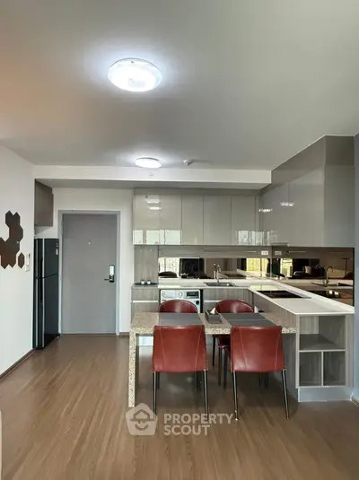 Modern kitchen with sleek cabinetry and dining area in open layout apartment.