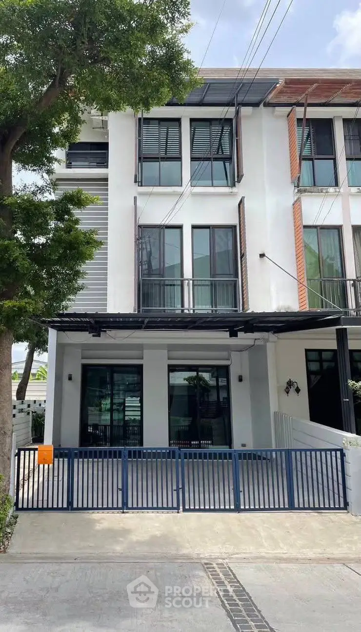 Modern three-story townhouse with sleek design and gated entrance in a suburban neighborhood.