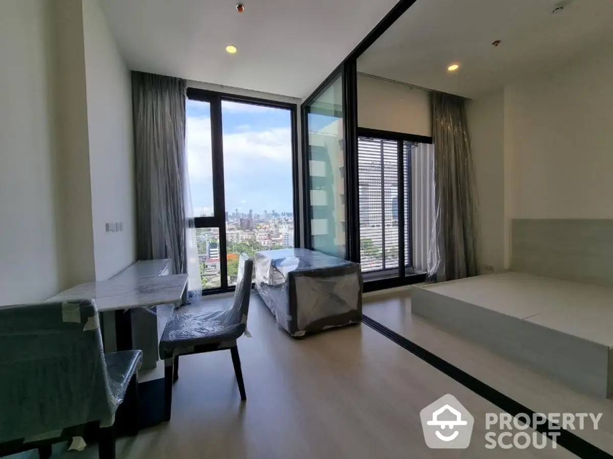 Modern apartment with city view, featuring large windows and sleek interior design.