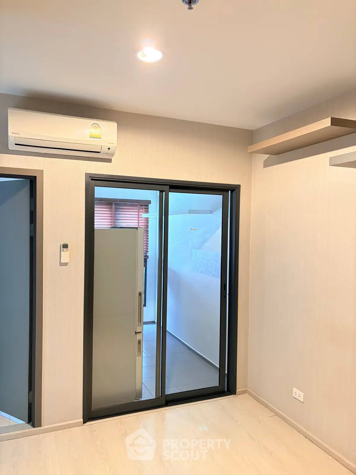 Modern apartment interior with air conditioning and sliding glass doors leading to a balcony.