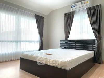 Spacious bedroom with large windows and modern bed frame