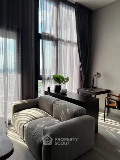Modern living room with large windows and stylish furniture, offering a bright and inviting atmosphere.