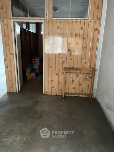 Spacious storage area with wooden paneling and concrete floor, ideal for organizing and storing items.