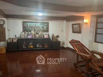 Spacious living room with polished hardwood floors and traditional decor, featuring a large wooden console and classic artwork.