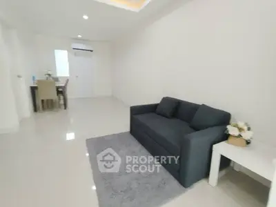 Spacious modern living room with sleek gray sofa and elegant dining area, perfect for contemporary living.