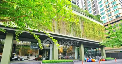 Modern building exterior with lush greenery and large windows in urban setting.