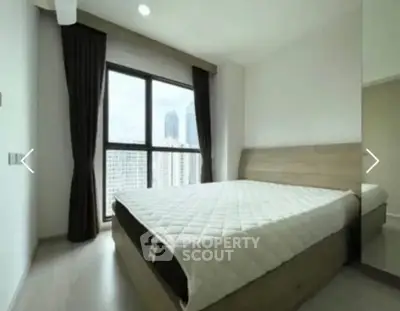 Modern bedroom with large window offering city view, featuring minimalist design and cozy atmosphere.