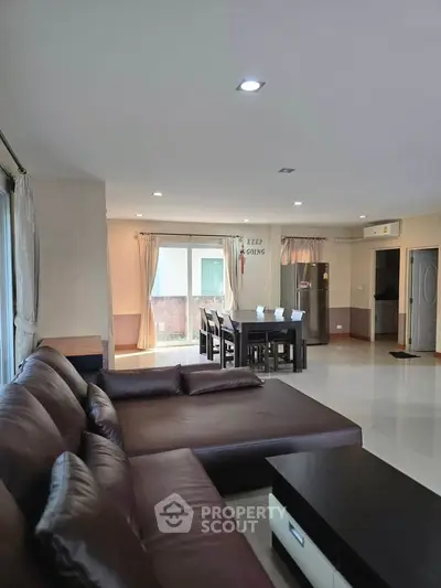 Spacious living room with modern furniture and open dining area, perfect for family gatherings.
