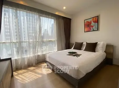 Bright and modern bedroom with large windows and stylish decor in city apartment.