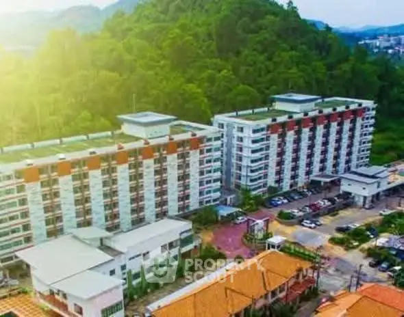 Aerial view of modern apartment complex surrounded by lush greenery and ample parking space.