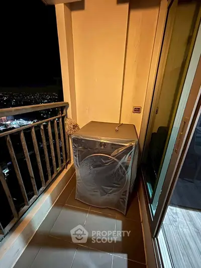 Cozy balcony with washing machine and city night view, perfect for urban living.