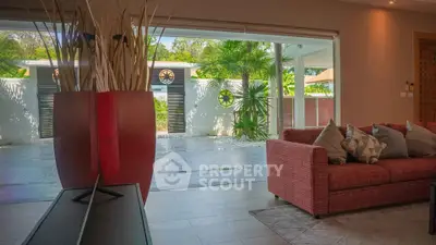 Spacious living room with modern decor and large sliding glass doors opening to a lush garden view.