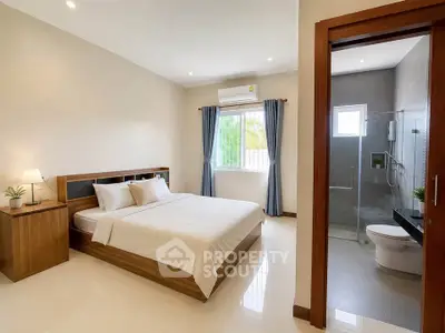 Spacious bedroom with ensuite bathroom and natural light in modern apartment.