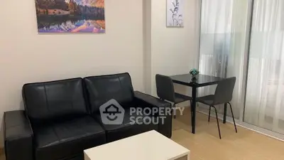 Modern living room with black leather sofa and dining table near balcony.